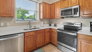 A kitchen with wooden cabinets, a stainless steel dishwasher, a built-in oven, and a microwave. - Shoreline Retreat (Gulfport)