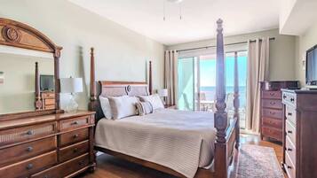 A spacious bedroom with a large bed, wooden furniture, a dresser, and a television.