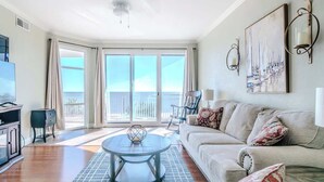 A spacious living room with a large window, a sofa, a coffee table, and a TV.