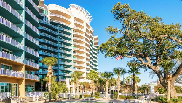 A hotel with a pool area, multiple balconies, and palm trees. - Beachview Condo at Legacy Tower 2 -1103 - Fully Furnished 2 Bedroom 2 Bath (Gulfport)