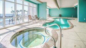 A pool area with two hot tubs, a seating area with chairs, and large windows offering a view of the beach. - Beachview Condo in Legacy Tower1 -303 - With Reserved Parking Spot in Front (Gulfport)