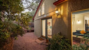 A cozy outdoor area with a gravel path, a wooden bench, and potted plants. - Stylish Garden Casita under the Trees (Sedona)