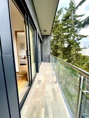 Un balcon moderne offrant une vue sur les arbres et le paysage urbain.
