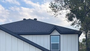 A two-story house with a dark garage door, a small window with blinds, and a dark front door. -  Modern 4BR/2.5BA Townhouse in the Heart of Fort Worth (Fort Worth)