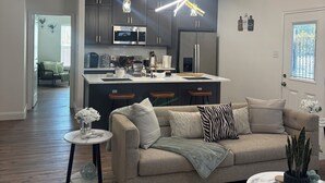 A modern kitchen with dark cabinets, a central island, and pendant lighting. -  Modern 4BR/2.5BA Townhouse in the Heart of Fort Worth (Fort Worth)