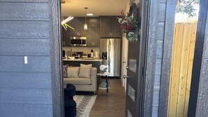 A modern home interior with a kitchen, living area, and a door with a 'welcome' mat. -  Modern 4BR/2.5BA Townhouse in the Heart of Fort Worth (Fort Worth)