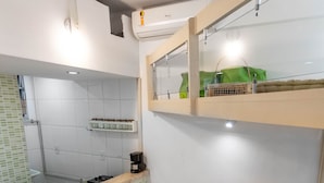 A compact kitchen with a sink, stove, and countertop. There is a small dining area with two stools and a sofa with a blanket. - 1 Minuto Da Praia De Copacabana | A923 (Rio de Janeiro)