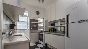 A modern kitchen with a black and white checkered floor, a built-in oven, and a stainless steel refrigerator. - Vista Para O Mar 50 Metros Da Praia | Bi701 (Rio de Janeiro)