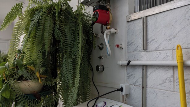 A front-loading washing machine with a water tank, a red water heater, and a potted fern plant. - Vista Para O Mar 50 Metros Da Praia | Bi701 (Rio de Janeiro)