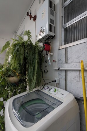 A front-loading washing machine with a water tank, a red water heater, and a potted fern plant. - Vista Para O Mar 50 Metros Da Praia | Bi701 (Rio de Janeiro)