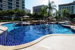 A swimming pool with a rock feature, palm trees, and a bridge. - Suíte Piscina E Academia | Bpremium T1 1208.4 (Rio de Janeiro)