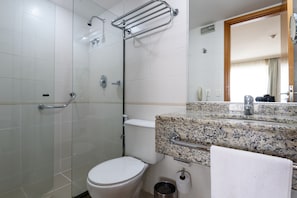 A bathroom with a glass shower enclosure, a white toilet, a granite countertop, and a mirror. - Suíte Piscina E Academia | Bpremium T1 1208.4 (Rio de Janeiro)