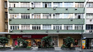 A multi-story building with air conditioning units, a storefront with a red awning, and a gated entrance. - Sossego Em Copa | Vista Arborizada | Br1009 (Rio de Janeiro)