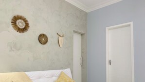 A room with a white sofa, a patterned throw blanket, and decorative wall hangings. - 6 Minutos Da Praia De Copacabana | Br1033 (Rio de Janeiro)