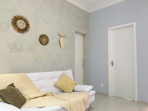 Ein Zimmer mit einer weißen Couch, einer gemusterten Decke und Wandgestaltungen.