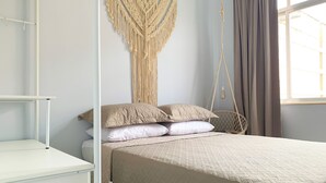 A bedroom with a bed, a macrame wall hanging, a hanging chair, and a window with curtains. - 6 Minutos Da Praia De Copacabana | Br1033 (Rio de Janeiro)