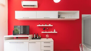 A modern living room with a red wall, white furniture, a flat-screen TV, and a glass door leading to a balcony. - Perfeito Em Copacabana |Quarto Confortável| Br401 (Rio de Janeiro)