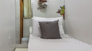 A small, clean room with a bed, a bedside table, a mirror, and a shelf with a hanging bag. - Estilo Em Copacabana | Próximo A Praia | Br403 (Rio de Janeiro)