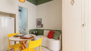 Ein Essbereich mit einem weißen Tisch, gelben Stühlen und einem weißen Sofa mit roten und grünen Kissen.