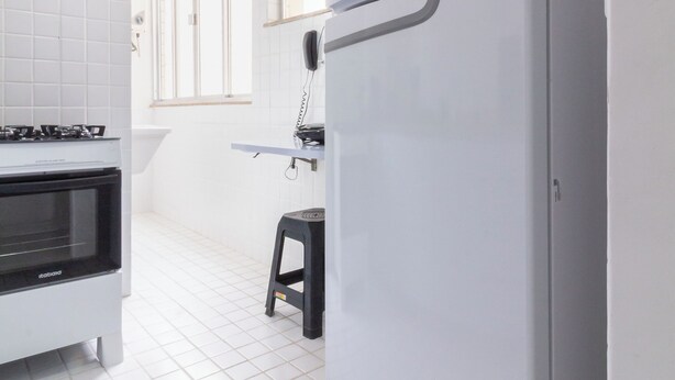 A kitchen with white tiled walls, a white refrigerator, a stove, and a small stool. - Conforto A 6Min Da Praia De Copacabana | Br801 (Rio de Janeiro)