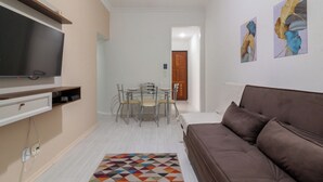 A modern living room with a flat-screen TV, a brown sofa, a dining table with chairs, and two wall-mounted paintings. - Conforto A 6Min Da Praia De Copacabana | Br801 (Rio de Janeiro)