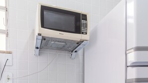 A kitchen with a microwave, a small stool, and a white countertop. - Conforto A 6Min Da Praia De Copacabana | Br801 (Rio de Janeiro)