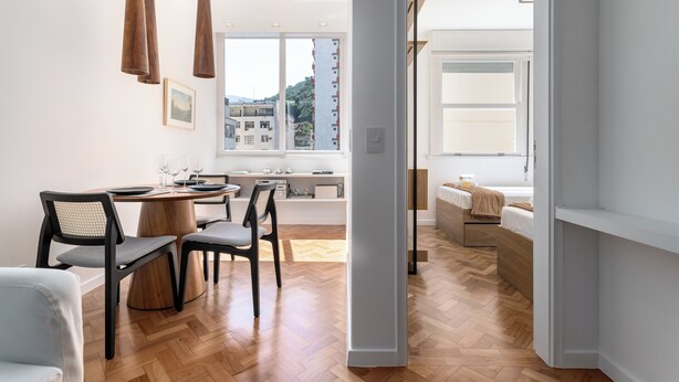 A modern interior with a dining area, a bed, and a view of buildings outside. - 5 Minutos Da Praia E Vista Para O Cristo | Br904 (Rio de Janeiro)