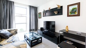 A modern living room with a sofa, glass coffee table, black entertainment unit, and a large TV. - Excelente Em Ipanema |Ambiente Familiar| Bt101 (Rio de Janeiro)
