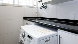 A laundry room with a washing machine, cabinets, and a black countertop. - Excelente Em Ipanema |Ambiente Familiar| Bt101 (Rio de Janeiro)