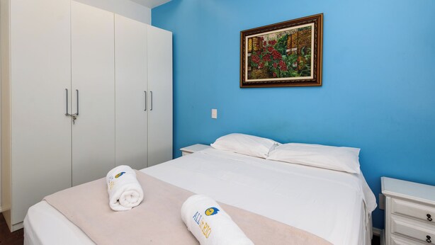 A hotel room with a bed, white wardrobe, and a painting on the wall. - Excelente Em Ipanema |Ambiente Familiar| Bt101 (Rio de Janeiro)