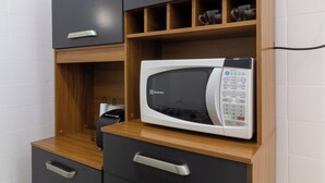 A kitchenette with a microwave, wooden shelves, and black cabinets. - 7 Minutos Da Praia De Ipanema | Bt201 (Rio de Janeiro)