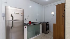 A compact kitchen with a stainless steel refrigerator, a small sink, and a gas stove. - 7 Minutos Da Praia De Ipanema | Bt201 (Rio de Janeiro)
