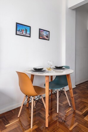 Un comedor con una mesa redonda, dos sillas y dos cuadros en la pared.