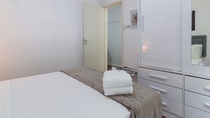 Un dormitorio con cama, armario y espejo.
