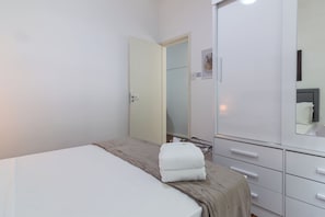 Une chambre Ă coucher avec un lit, une armoire et un miroir.
