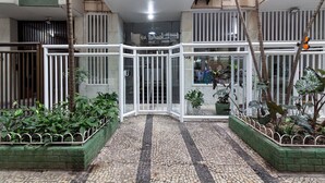 Una entrada de edificio con puerta de cristal, piso de baldosas y plantas en macetas.