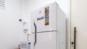 A compact kitchen with a white refrigerator, microwave, and a small wooden cabinet. - 10 Minutos Da Praia Do Flamengo Ao Lado Do Metrô | Ct404 (Rio de Janeiro)