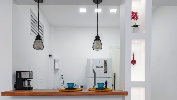 A modern kitchen with a wooden countertop, two bar stools, a coffee machine, and pendant lights. - 10 Minutos Da Praia Do Flamengo Ao Lado Do Metrô | Ct404 (Rio de Janeiro)