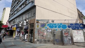 A tall building with multiple air conditioning units on the facade, a storefront with various signs, and graffiti on the lower part of the building. - 10 Minutos Da Praia Do Flamengo Ao Lado Do Metrô | Ct404 (Rio de Janeiro)