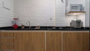 Une cuisine moderne avec des carreaux de céramique blancs disposés en motif métro, un mixeur rouge, un grille-pain et des armoires en bois.