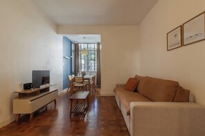 Ein Wohnzimmer mit Sofa, Fernseher und Essbereich mit Tisch und Stühlen.