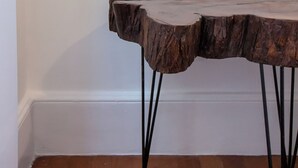 A corner of a room with a wooden table with a unique design and black metal legs. - Espaço E Conforto Em Copacabana | D405 (Rio de Janeiro)