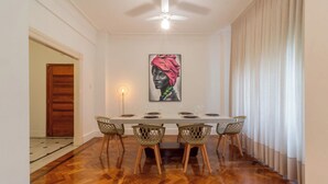 A dining area with a long table, six chairs, and a ceiling fan. - Espaço E Conforto Em Copacabana | D405 (Rio de Janeiro)