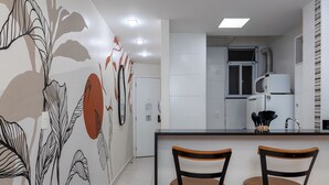A modern kitchen with a white countertop, two wooden stools, and a decorative wall mural. - 3 Minutos Da Praia De Copacabana | Df219 (Rio de Janeiro)