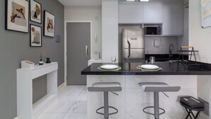 A modern kitchen with a central island, bar stools, a microwave, and a refrigerator. - Adorável A Poucos Minutos Do Pão De Açúcar | F709 (Rio de Janeiro)