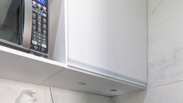 A modern kitchen with a black countertop, stainless steel sink, and a built-in microwave. - Adorável A Poucos Minutos Do Pão De Açúcar | F709 (Rio de Janeiro)