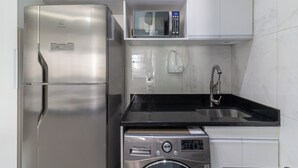 A compact kitchen with a stainless steel refrigerator, a microwave, and a washing machine. - Adorável A Poucos Minutos Do Pão De Açúcar | F709 (Rio de Janeiro)