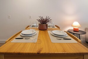 A dining table set with plates, cutlery, and a candle, with a plant centerpiece and a lit table lamp. - 4 Minutos Da Praia De Ipanema | Fa202 (Rio de Janeiro)