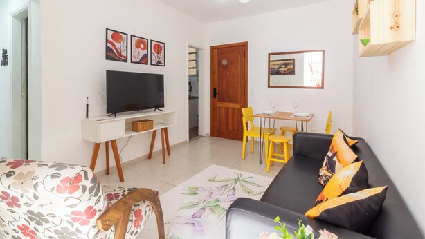 A living room with a sofa, a TV on a stand, a dining table with chairs, and a ceiling fan. - 14 Minutos Da Praia De Copacabana | Fo801 (Rio de Janeiro)