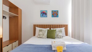 A hotel room with a wooden wardrobe, a bed with a blue blanket, two pillows, and two wall art pieces. - 14 Minutos Da Praia De Copacabana | Fo801 (Rio de Janeiro)